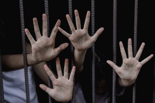 hands reaching through jail bars