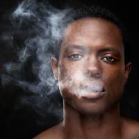 Young black man exhaling cannabis smoke