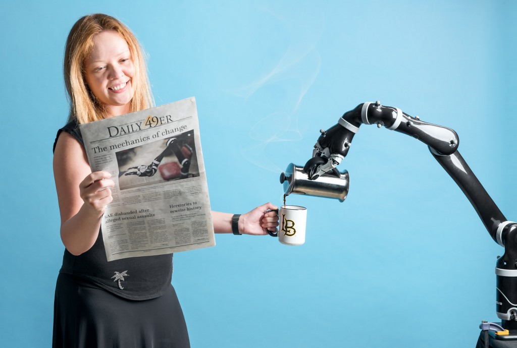 alt=“Dr. Emel Demircan receives a cup of coffee from a robotic arm”
