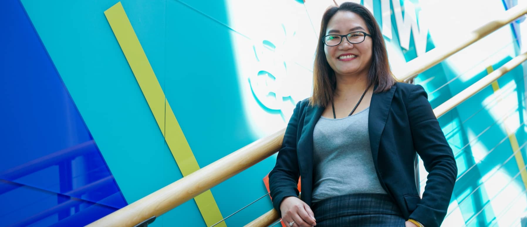 Person with glasses walking down steps smiling