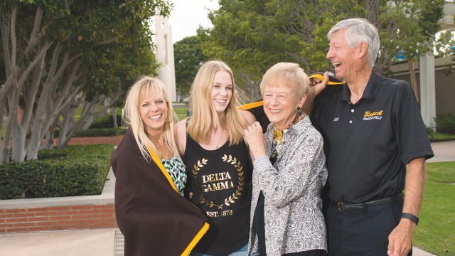 Alison and Nicole Chennault pose under a vintage Long Beach State blanket with Jan and Dale Fairbanks. They comprise three generations of CSULB family.