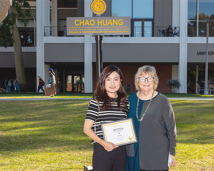 Chao Huang with President Jane Conoley at Employee of the Month sign on Friendship Walk