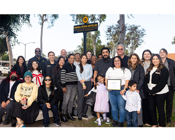Brenda Medina Santillan with family, friends and coworkers ETOM signpost on Friendship Walk