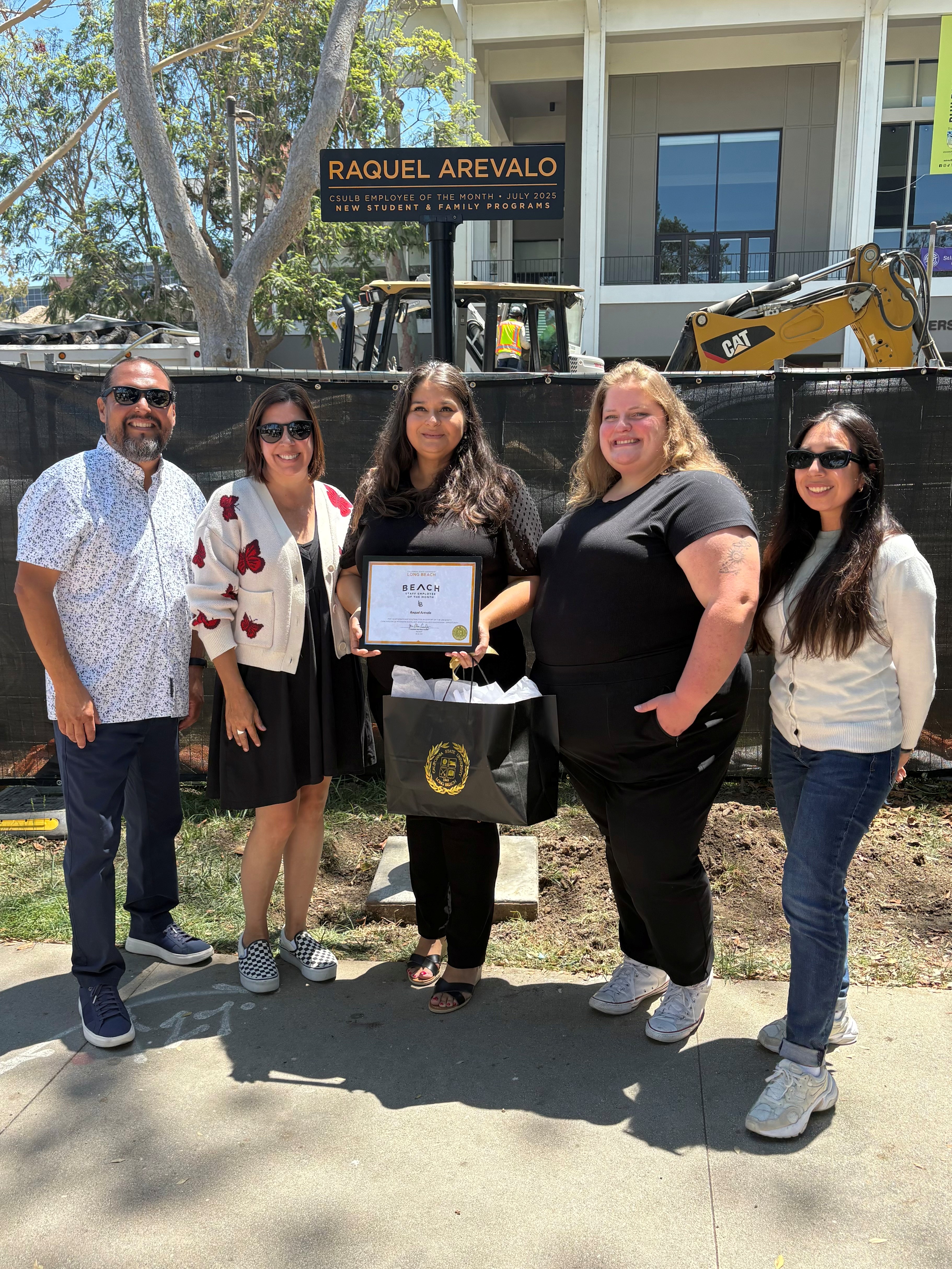 Raquel Arevalo with friends and coworkers ETOM signpost on Friendship Walk
