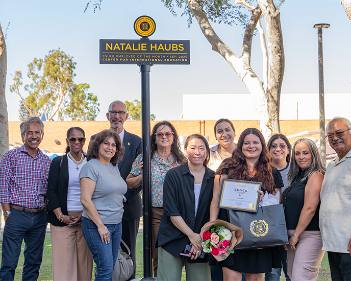 Natalie Haubs with friends and coworkers ETOM signpost on Friendship Walk